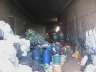 Vista do espaço de trabalho da Assoc. PE 2. Mesas e bombonas rodeadas por lixo que será triado